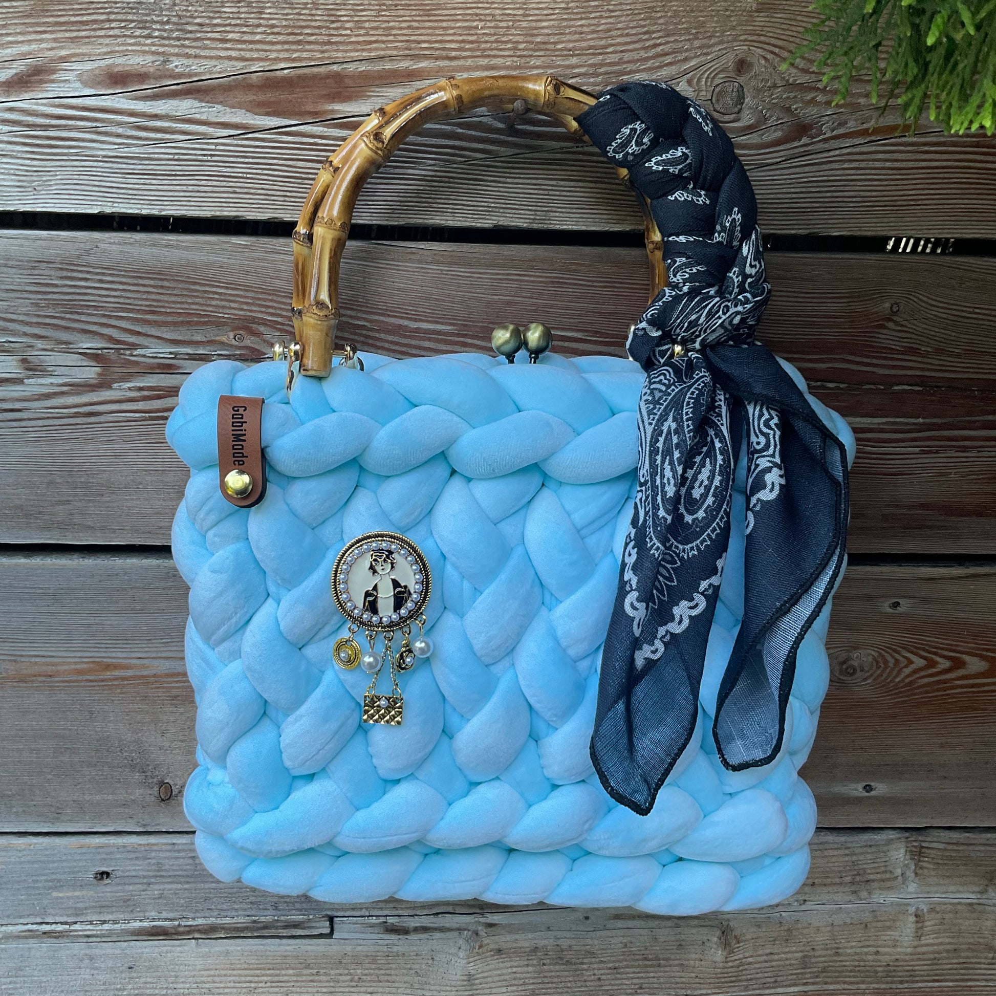 Eine hellblaue Trachtentasche mit Brosche und Tuch 