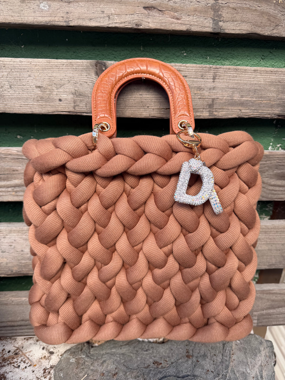 Eine gestrickte cognacfarbene Tasche mit Griffen und Anhänger 