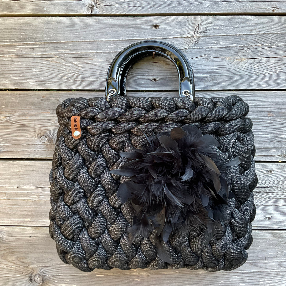 Eine schwarze gestrickte Tasche mit Silber und lackgriffen