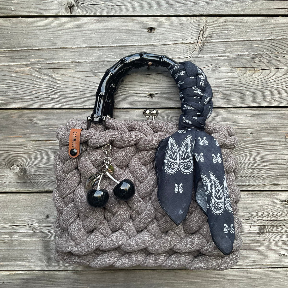 Eine gestrickte graue Trachtentasche mit Tuch und Bambusgriffen 