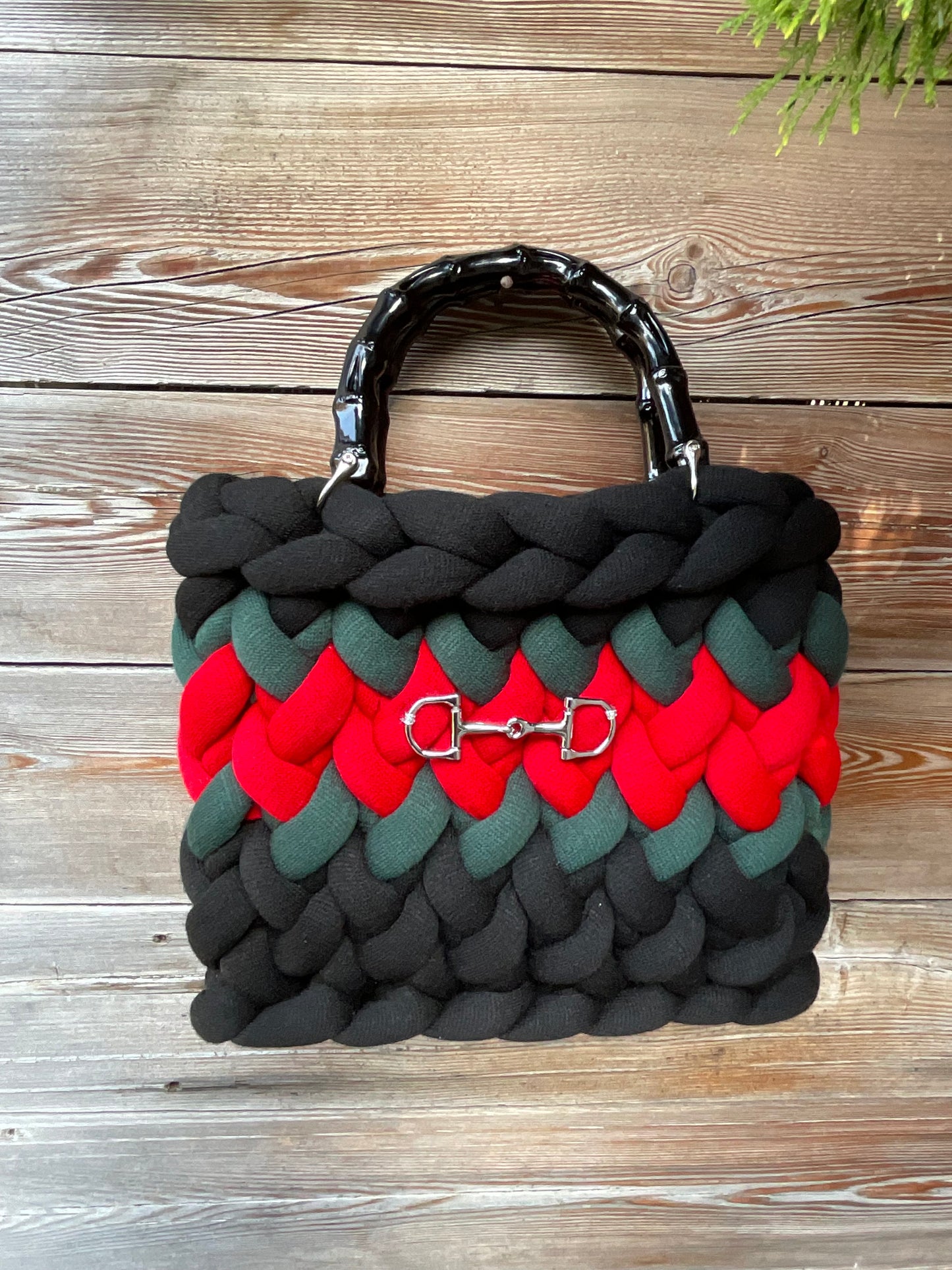 Eine schwarze gestrickte Tasche mit Streifen und Bambusgriffen 