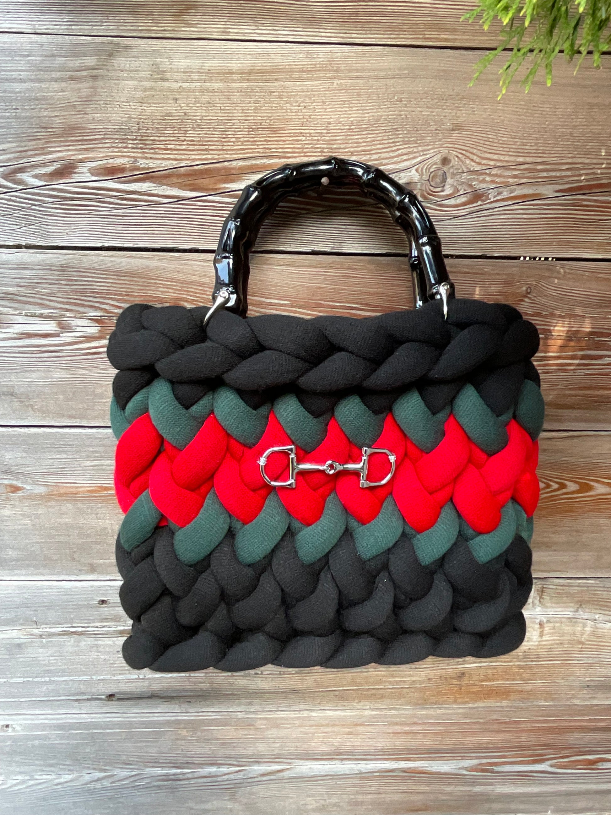 Eine schwarze gestrickte Tasche mit Streifen und Bambusgriffen 