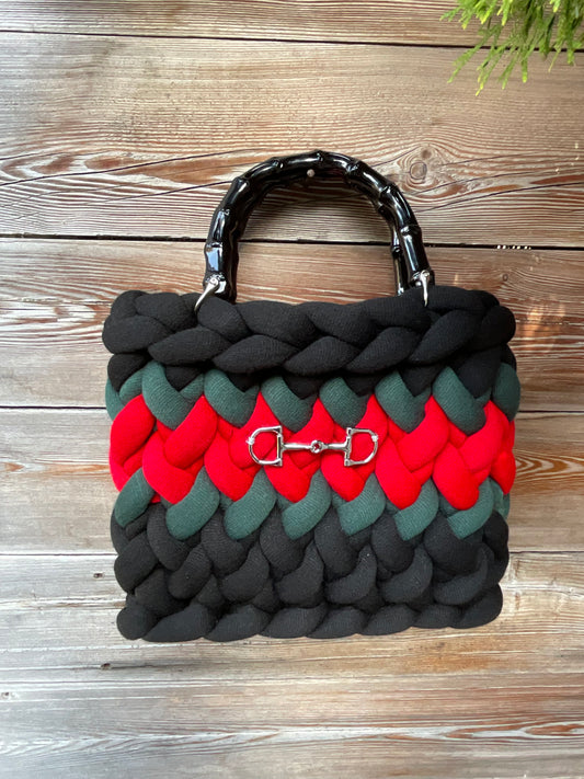 Eine schwarze gestrickte Tasche mit Streifen und Bambusgriffen 
