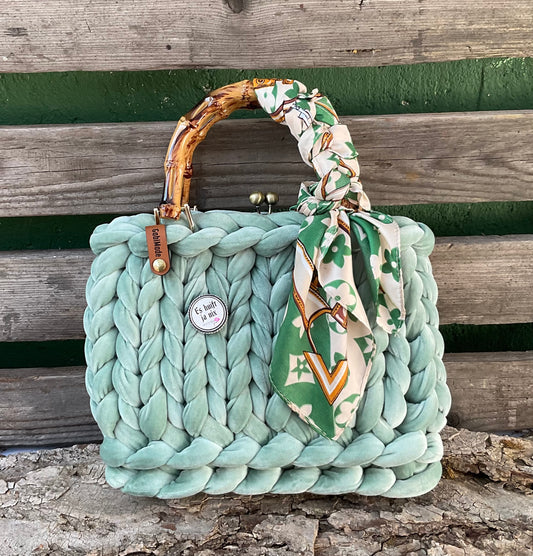 Eine grüne gestrickte Tasche mitbrachte und Griffen