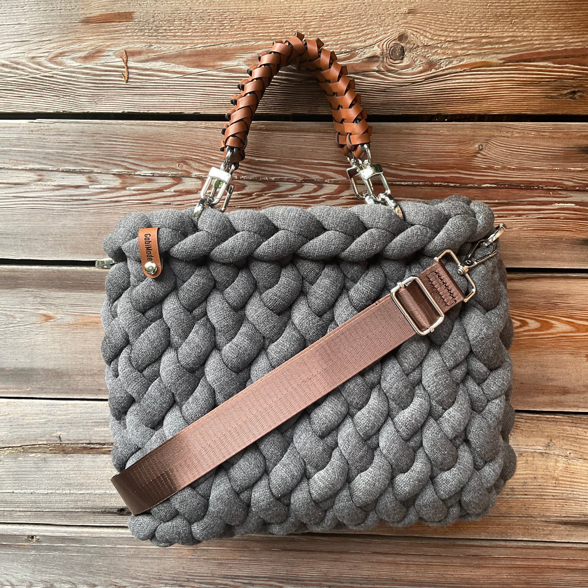 Eine graue gestrickte Tasche mit geflochtenen Griffen 