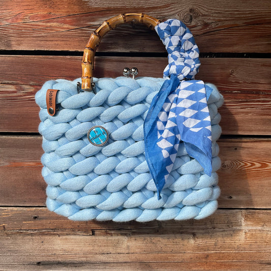 Eine hellblaue gestrickte Trachtentasche mit Bambusgriffen 