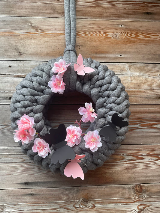 Ein gestrickter grauer Kranz mit Dekoration 