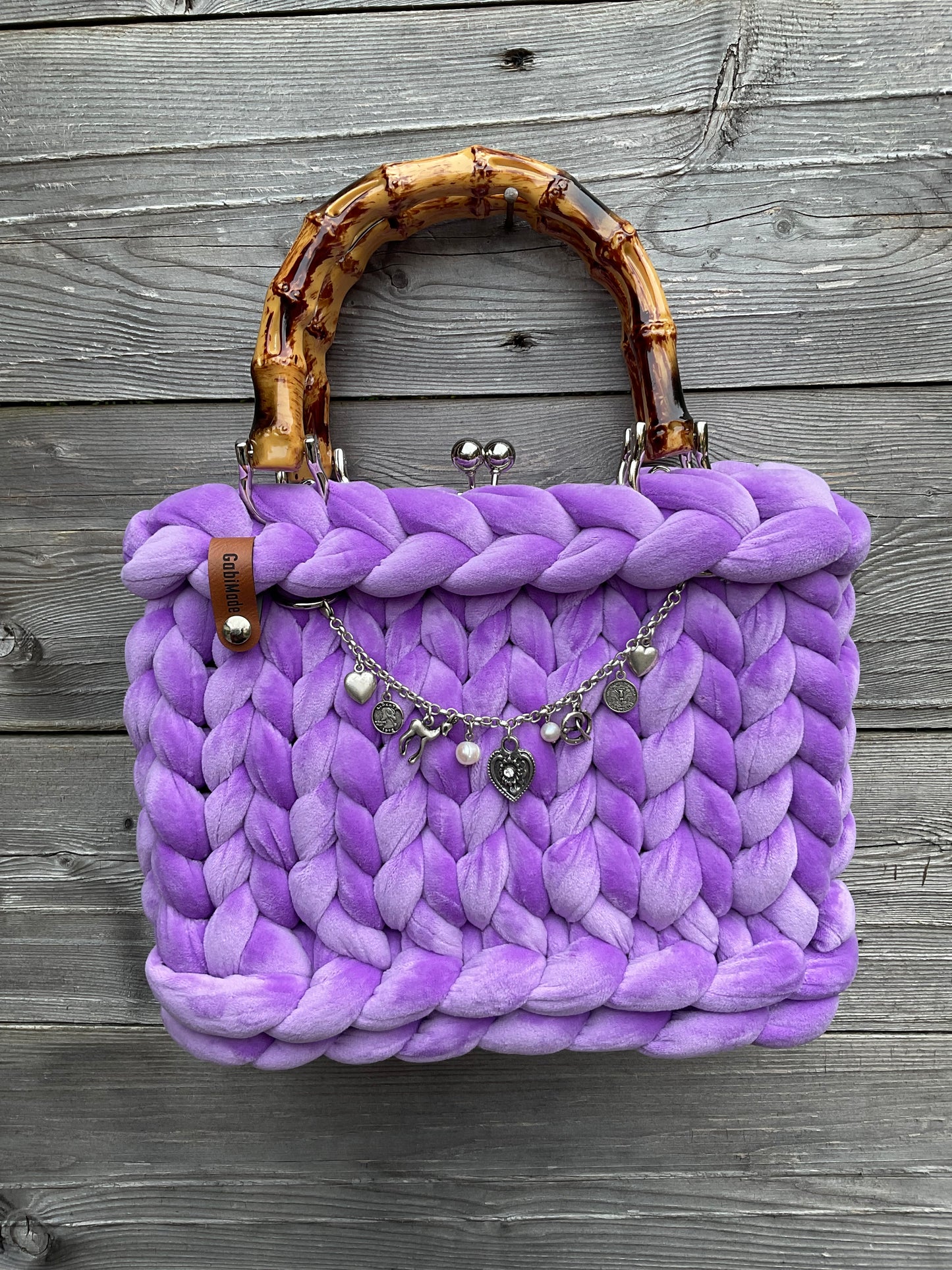 Eine gestrickte lila Trachtentasche mit Charivari 
