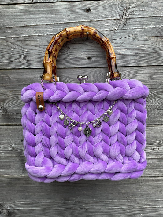 Eine gestrickte lila Trachtentasche mit Charivari 