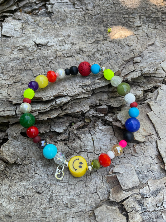 Ein buntes Armband mir einer gelben Smileyperle und einem silbernen Herzanhänger