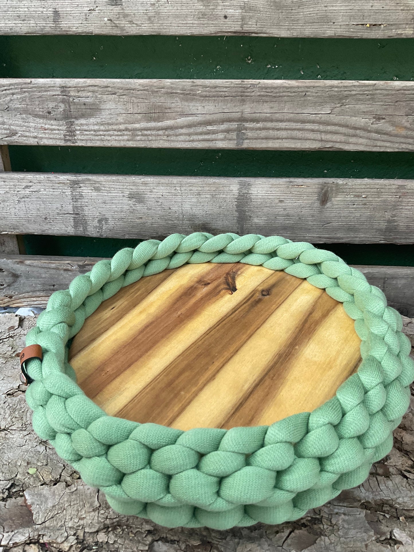 Ein grünes gestricktes Tablett mit Holzteller