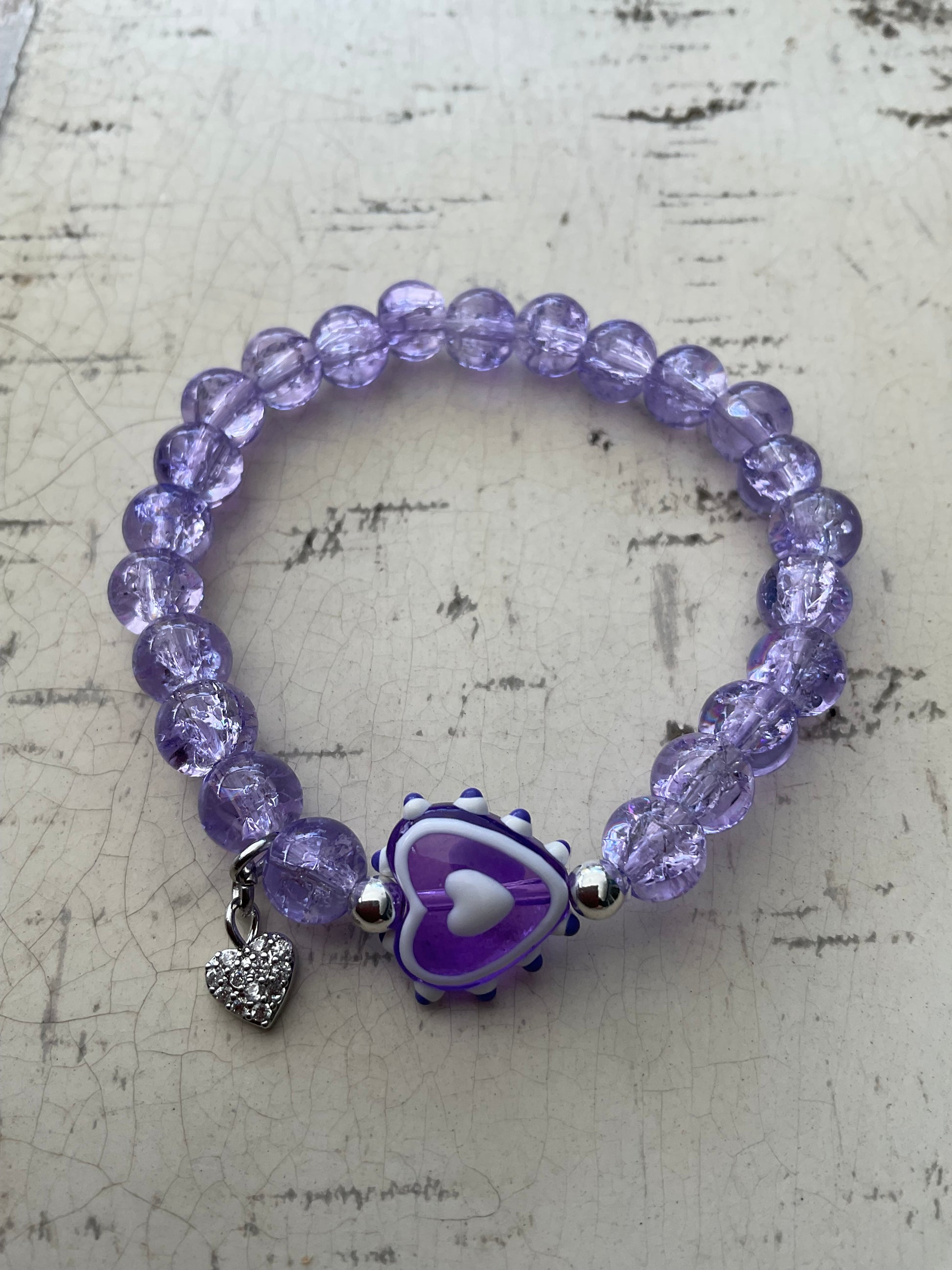 Ein violettes perlenarmband mit Herzperle 