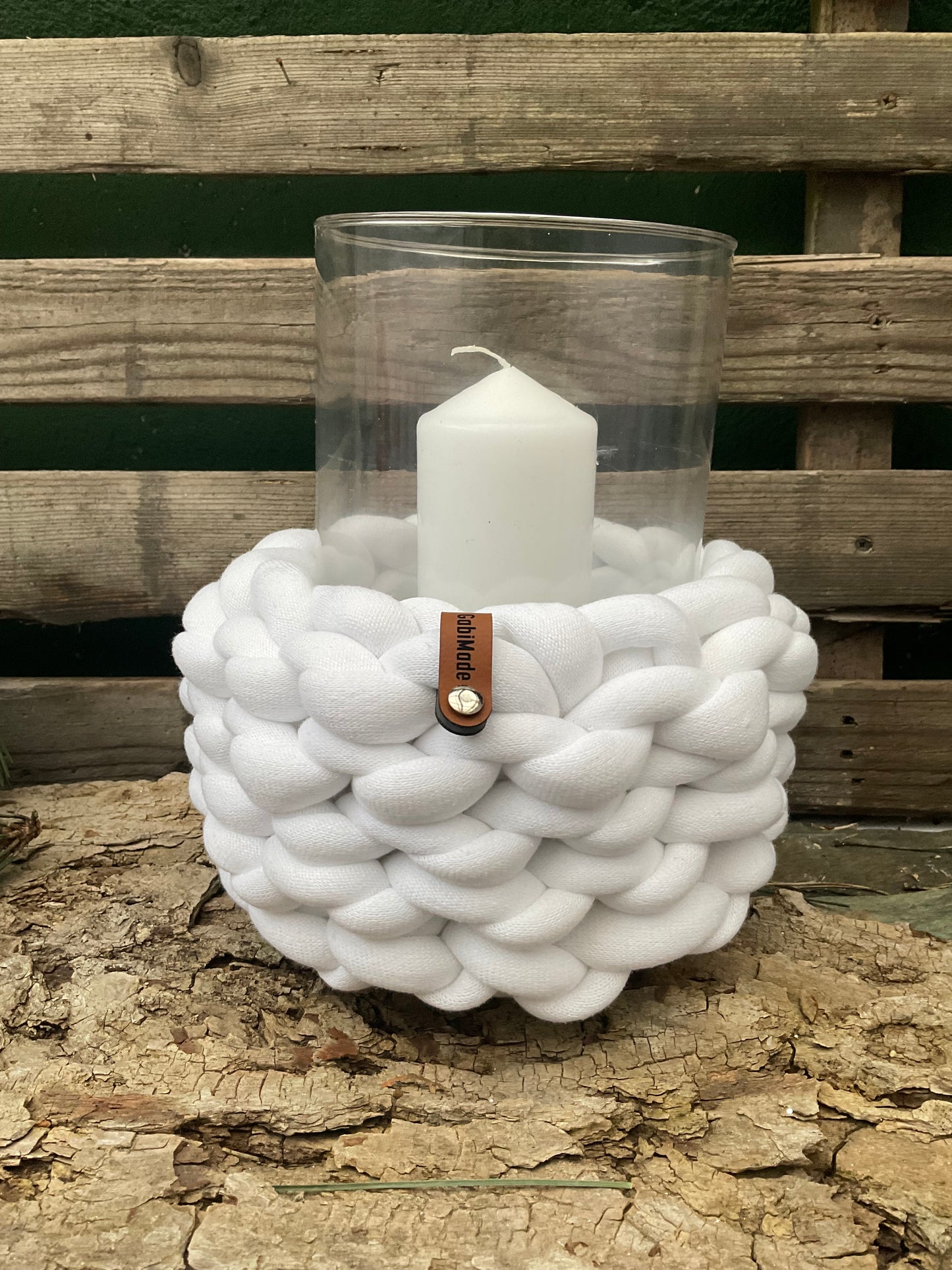 Ein weißes gestricktes Windlicht mit Glaseinsatz 