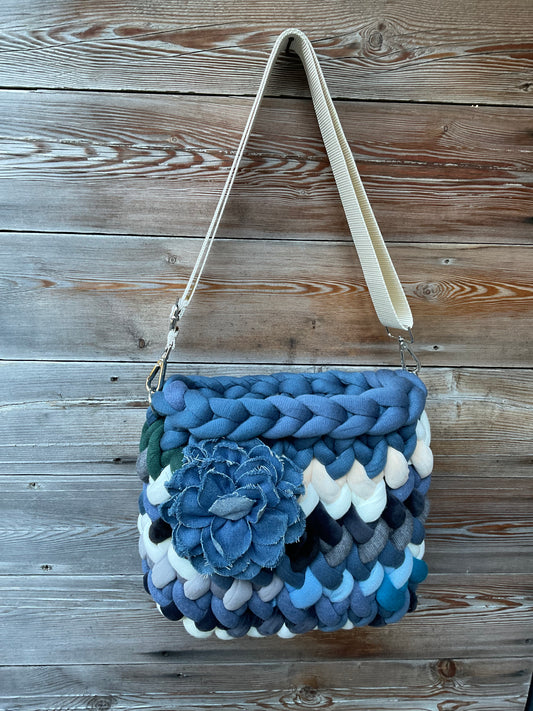 Eine gestrickte Tasche in Blautönen  mit Schultergurt 