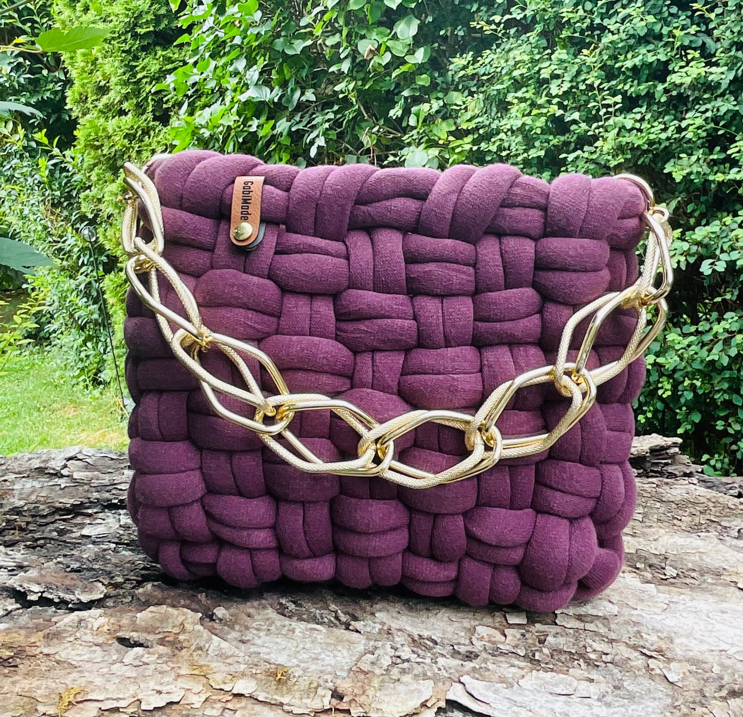 Eine Pflaumfarbene geknüpfte Tasche mit Goldkette