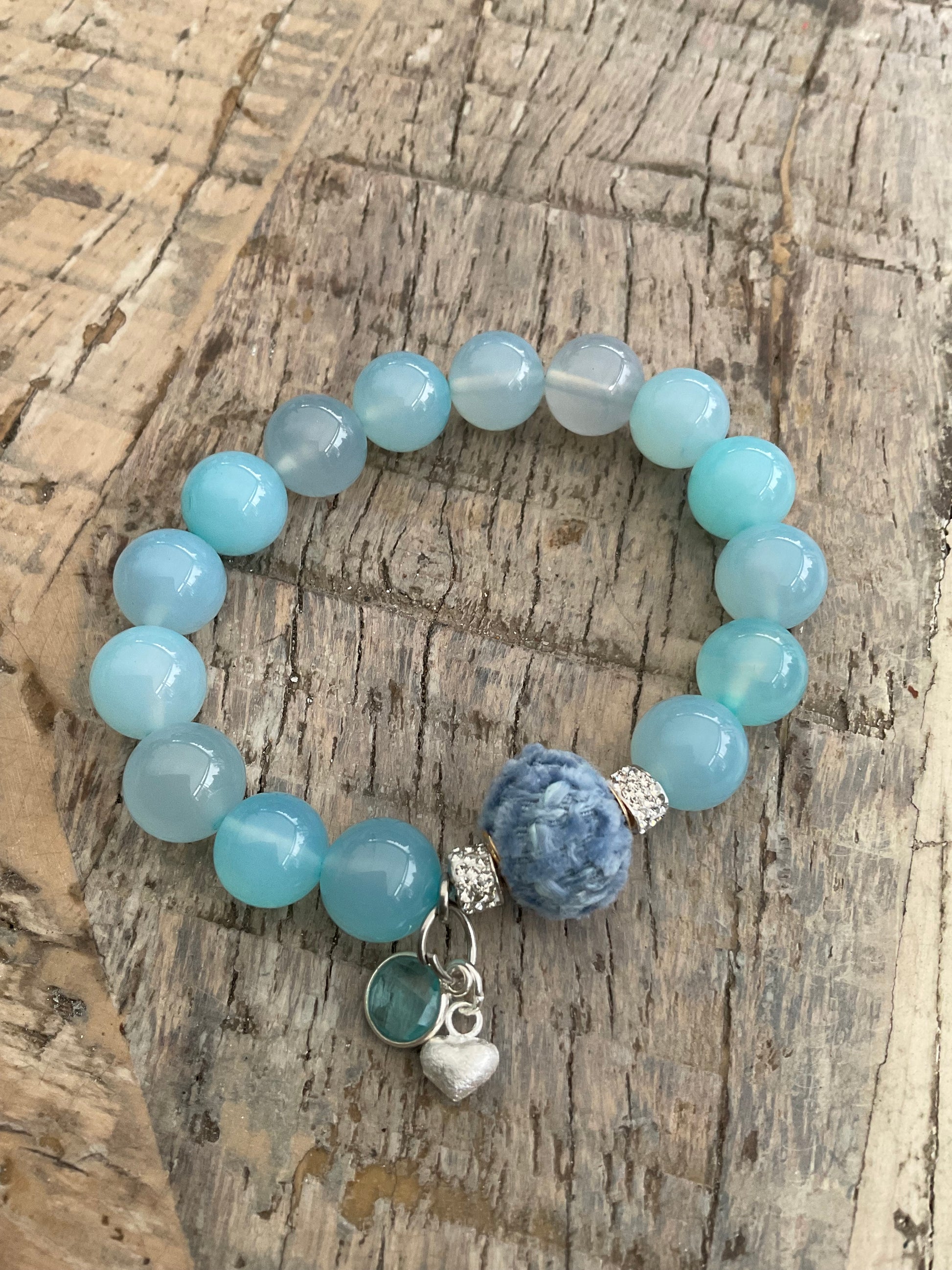 Ein hellblaues Perlenarmband mit einem Herzanhänger 