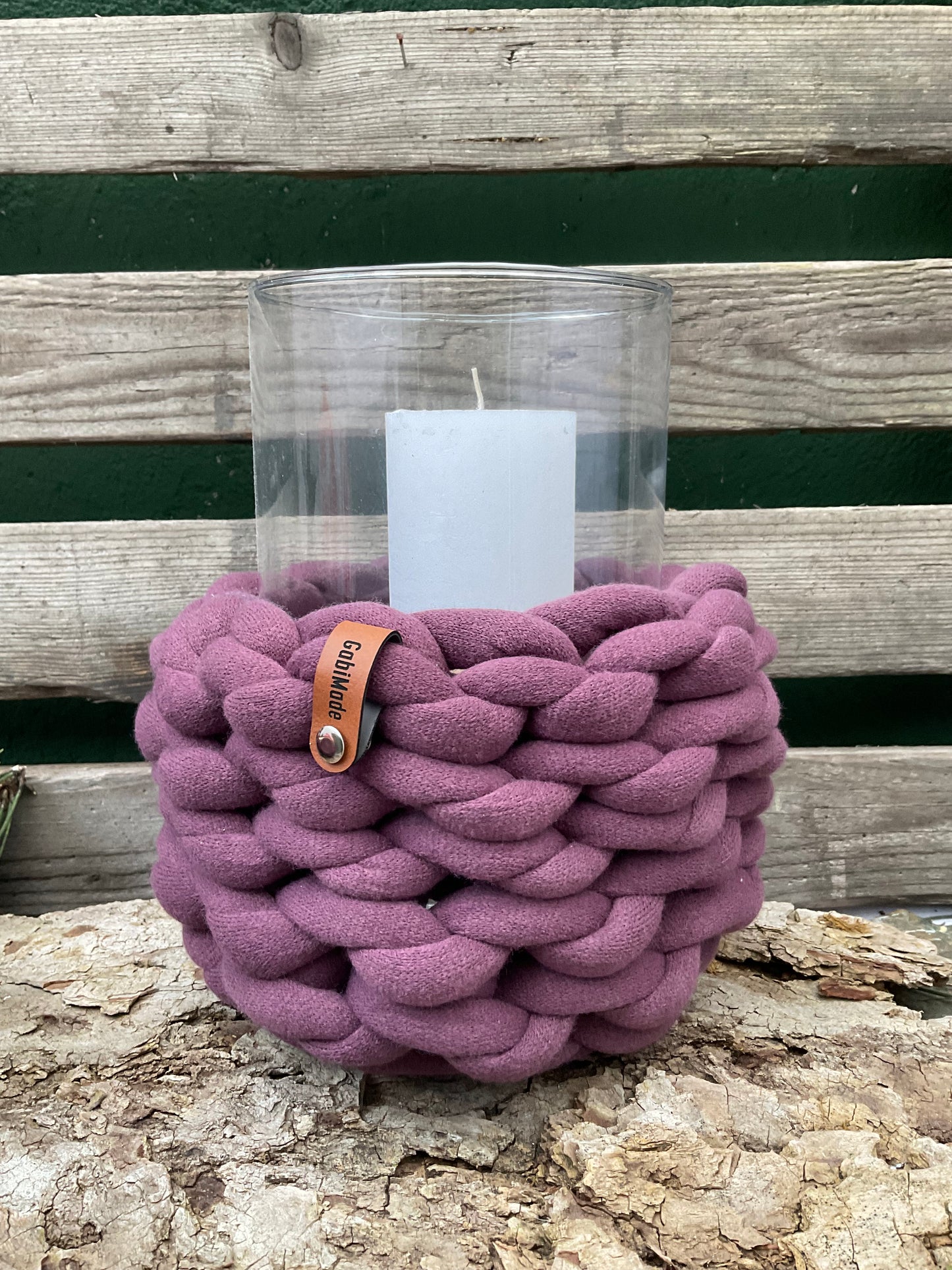 Ein gestricktes lila Windlicht mit Holzteller 