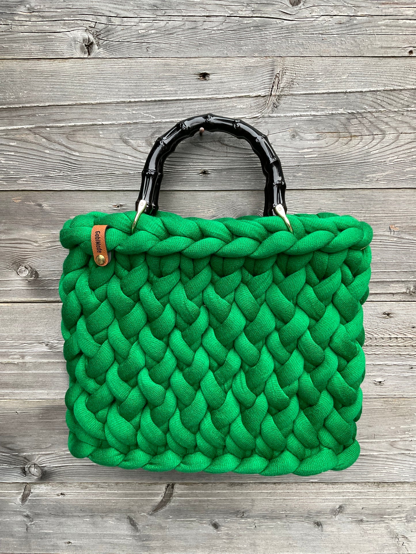 Eine grüne gestrickte Tasche mit Bambusgriffen 