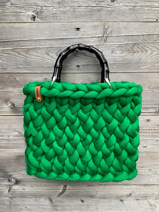 Eine grüne gestrickte Tasche mit Bambusgriffen 