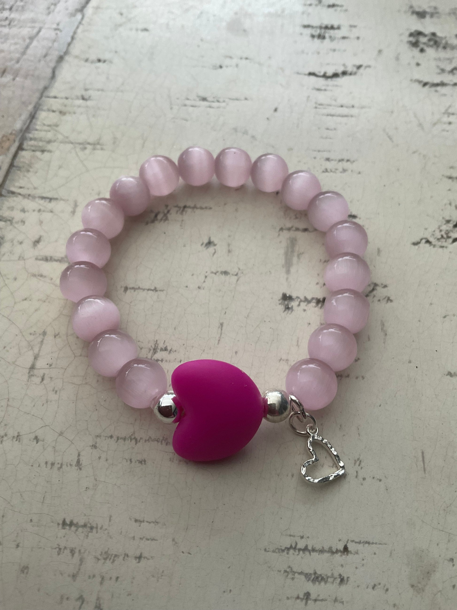 Ein rosa perlenarmband mit einem pinken Herz 