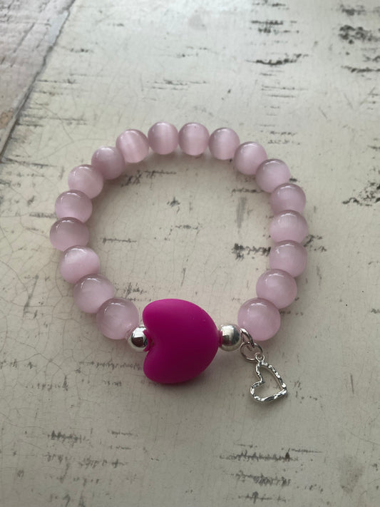 Ein rosa perlenarmband mit einem pinken Herz 