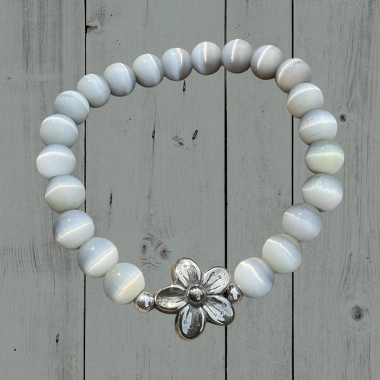 Ein hellgraues Armband mit einer silbernen Blumenperle