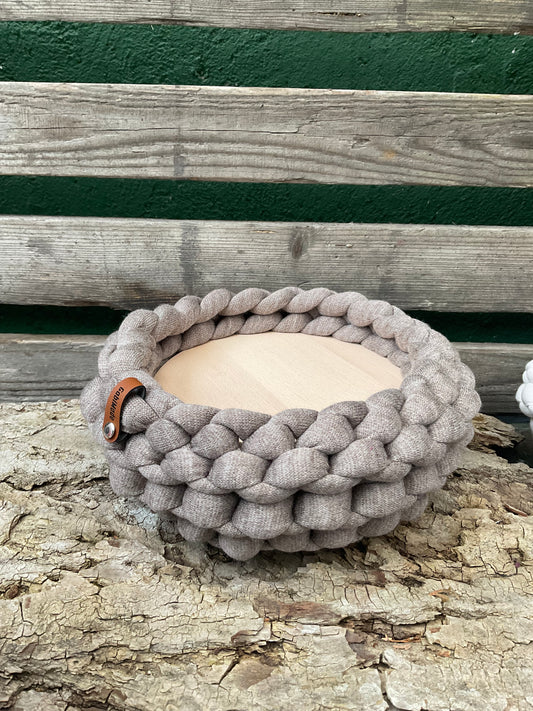 Ein hellbraunes gestricktes Tablett mit Holzteller 