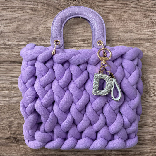 Eine gestrickte Tasche in lila mit Henkel 