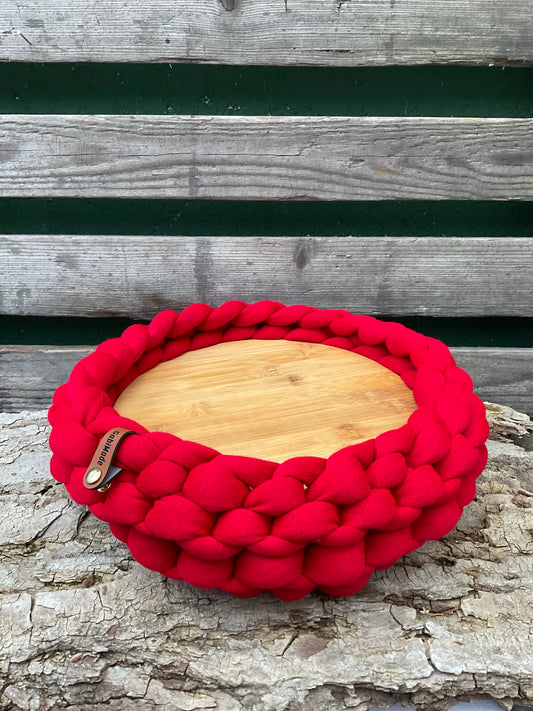 Ein gestricktes rotes Tablett mit Holzteller 