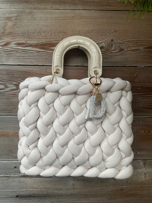Eine gestrickte Tasche in Creme mit Henkel 