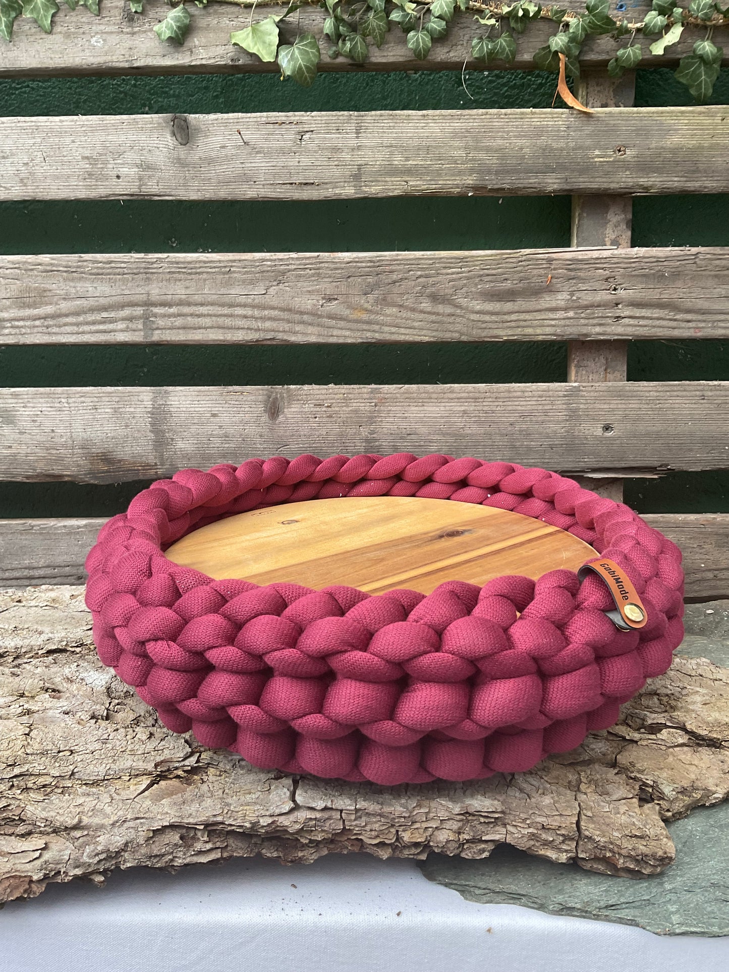 Ein gestricktes weinrotes Tablett mit Holzteller 