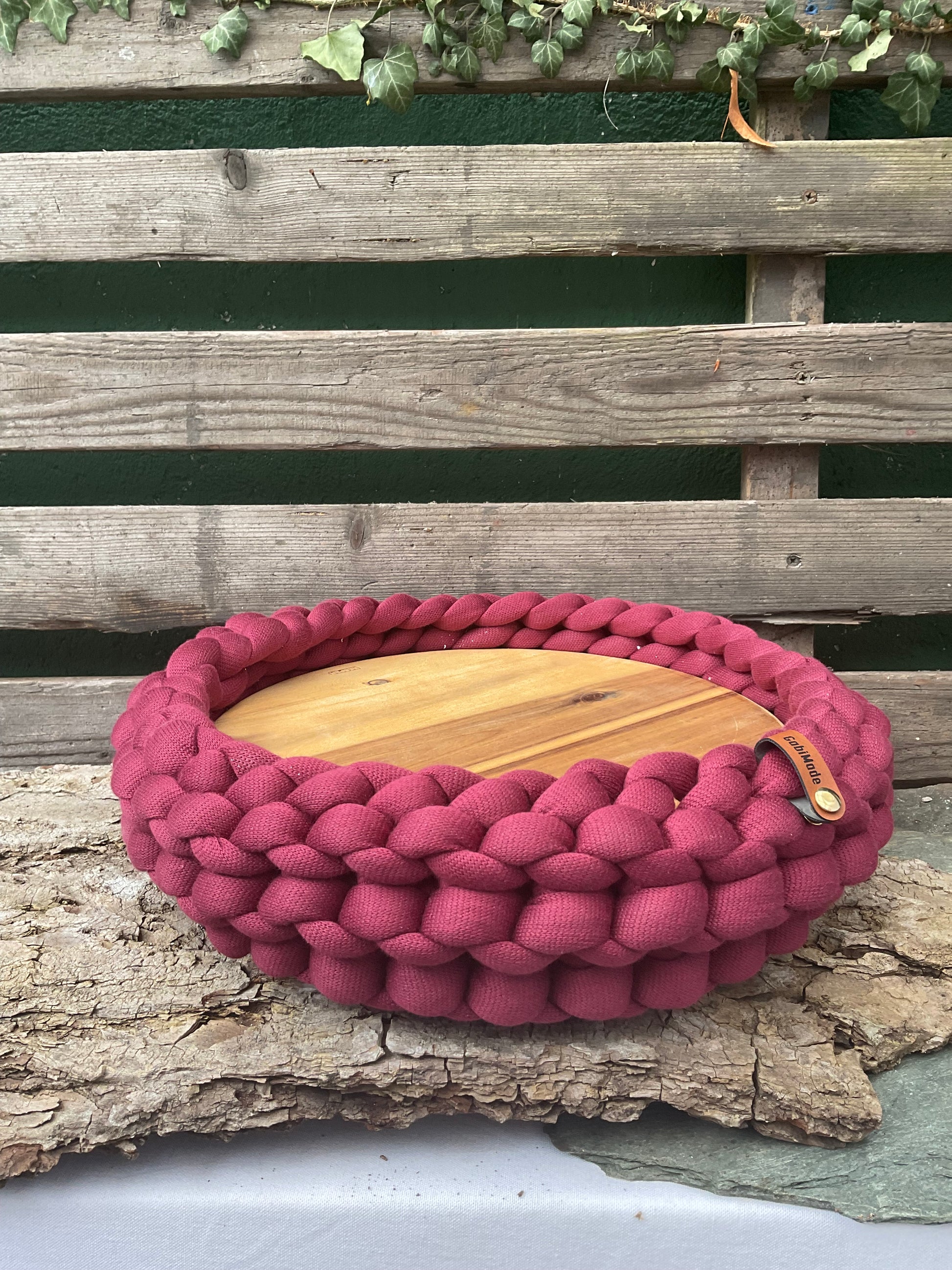 Ein gestricktes weinrotes Tablett mit Holzteller 