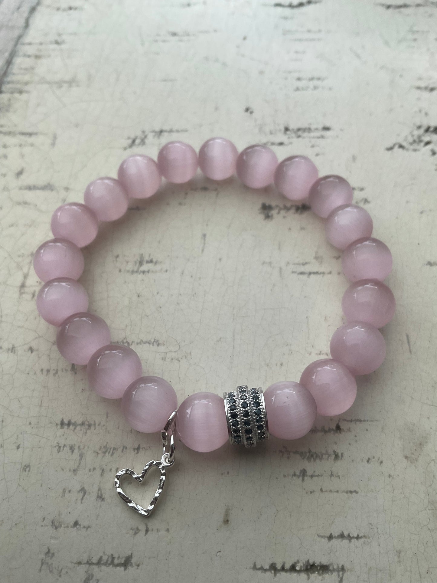 Ein rosa Perlenarmband mit Herzanhänger 