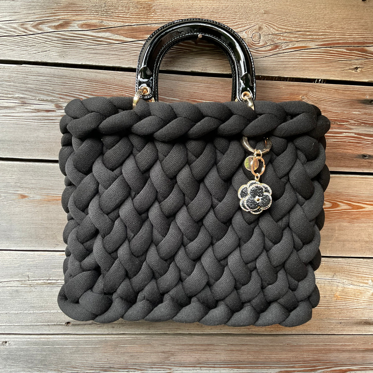 Eine gestrickte schwarze Tasche mit Henkeln und Anhänger 