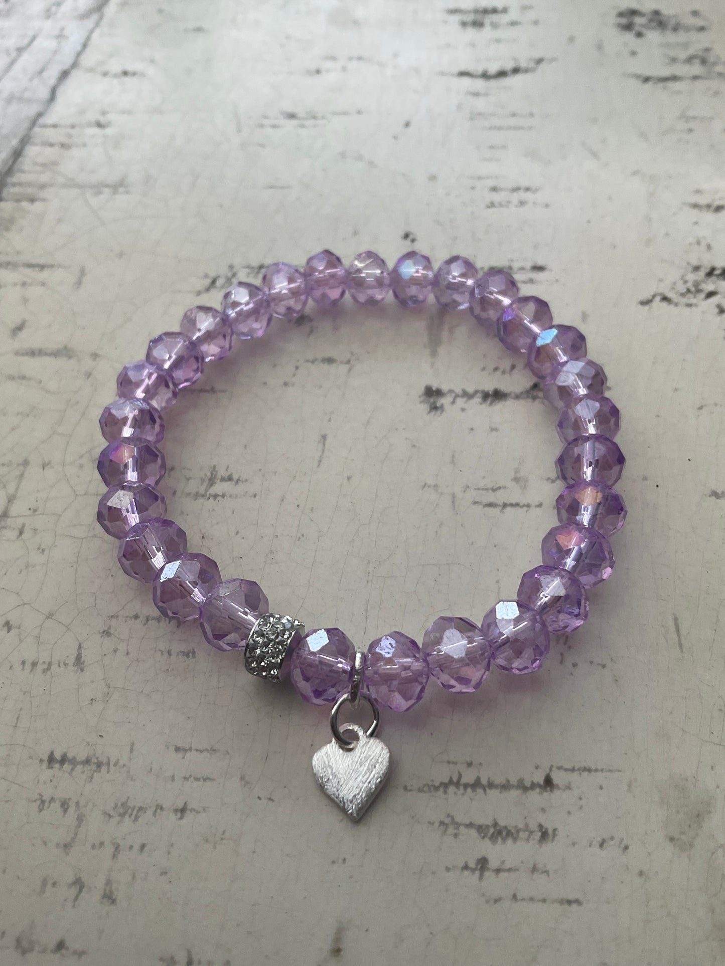 Ein lila perlenarmband mit Herzanhänger 