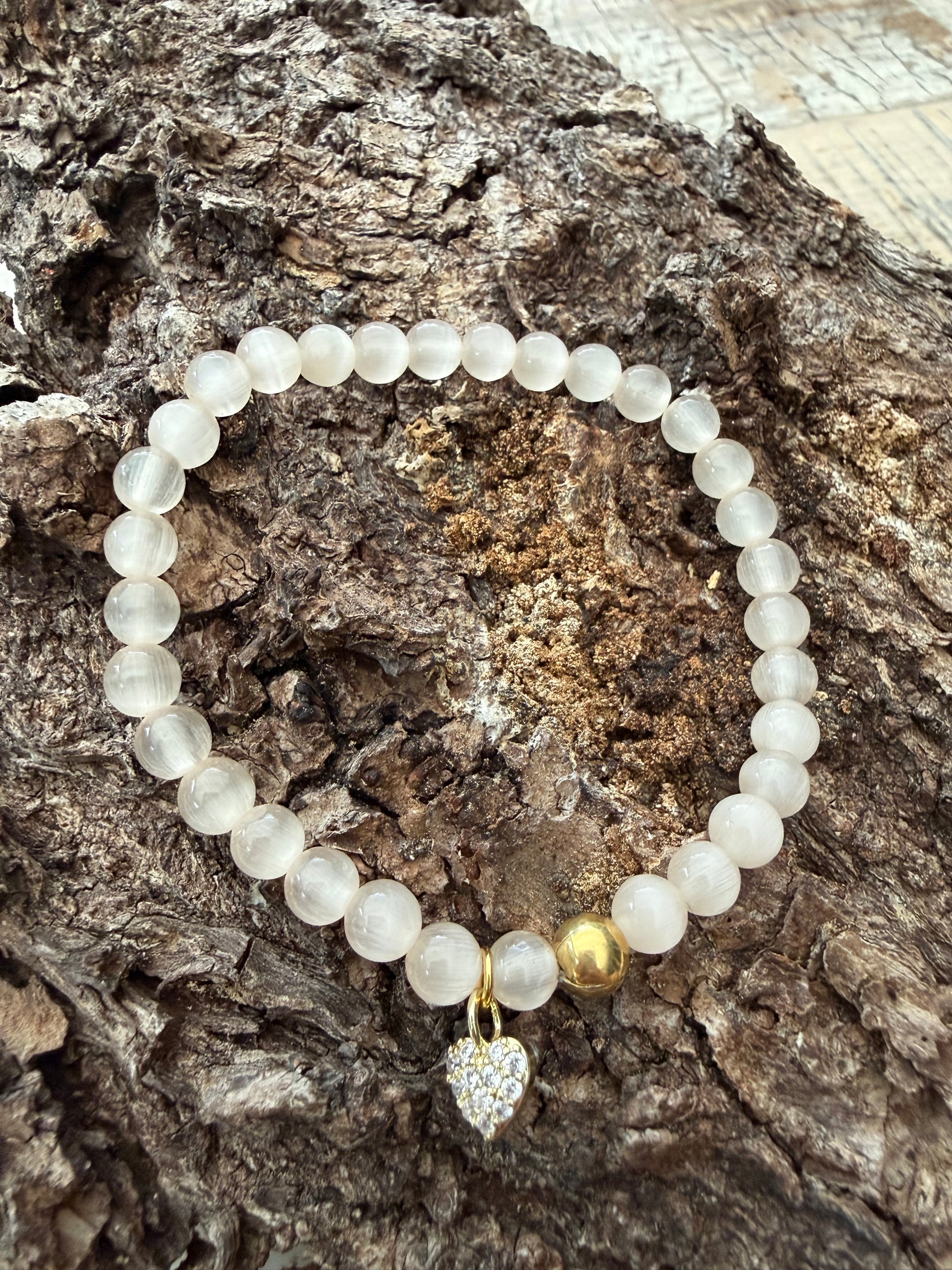 Ein cremefarbenes Perlenarmband mit Herzanhänger 