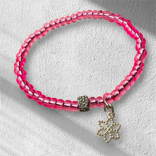Ein pinkes Perlenarmband mit Glitzer und Blumenanhänger 