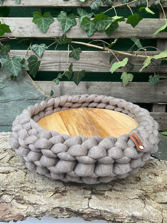 Ein gestricktes Hellbraunes Tablett mit Holzteller 