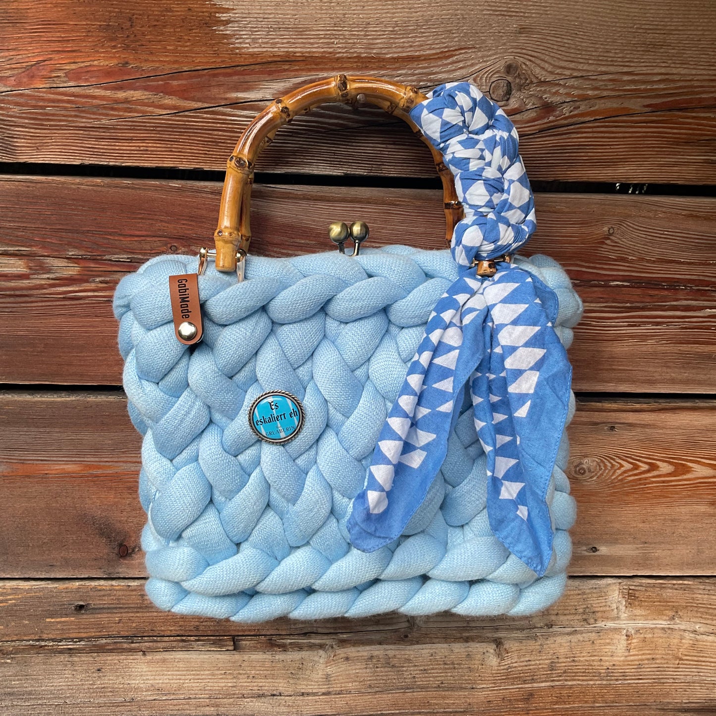 Eine gestrickte blaue Trachtentasche mit Bambusgriffen 