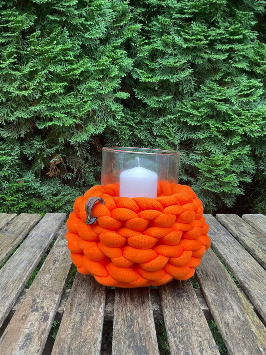 Ein gestricktes orangefarbenes Windlicht 