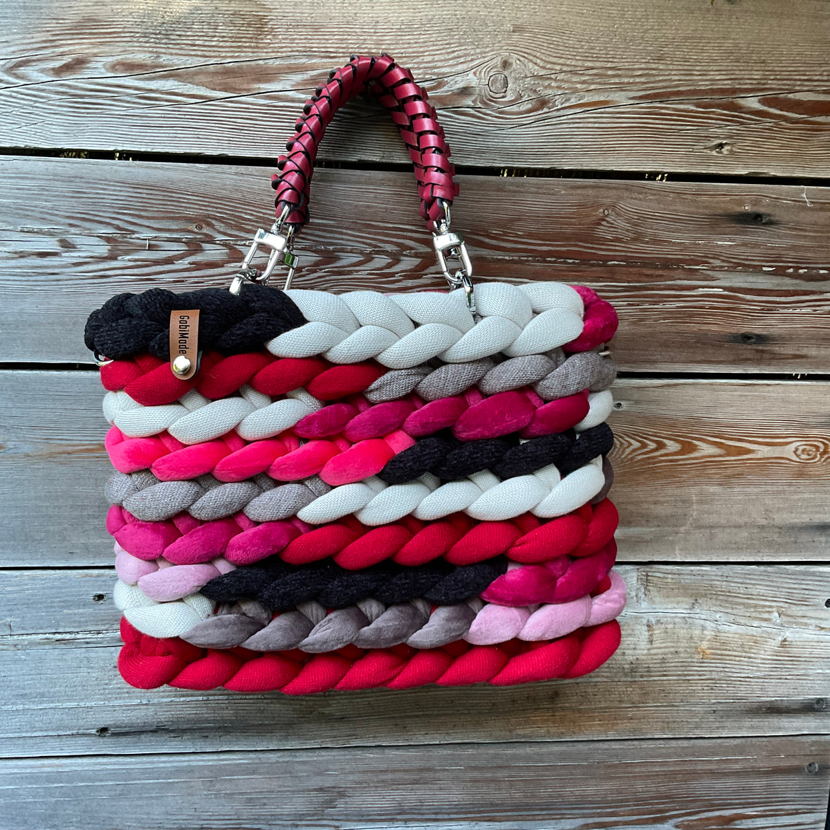 Eine gestrickte rote Tasche mit geflochtenen Griffen 