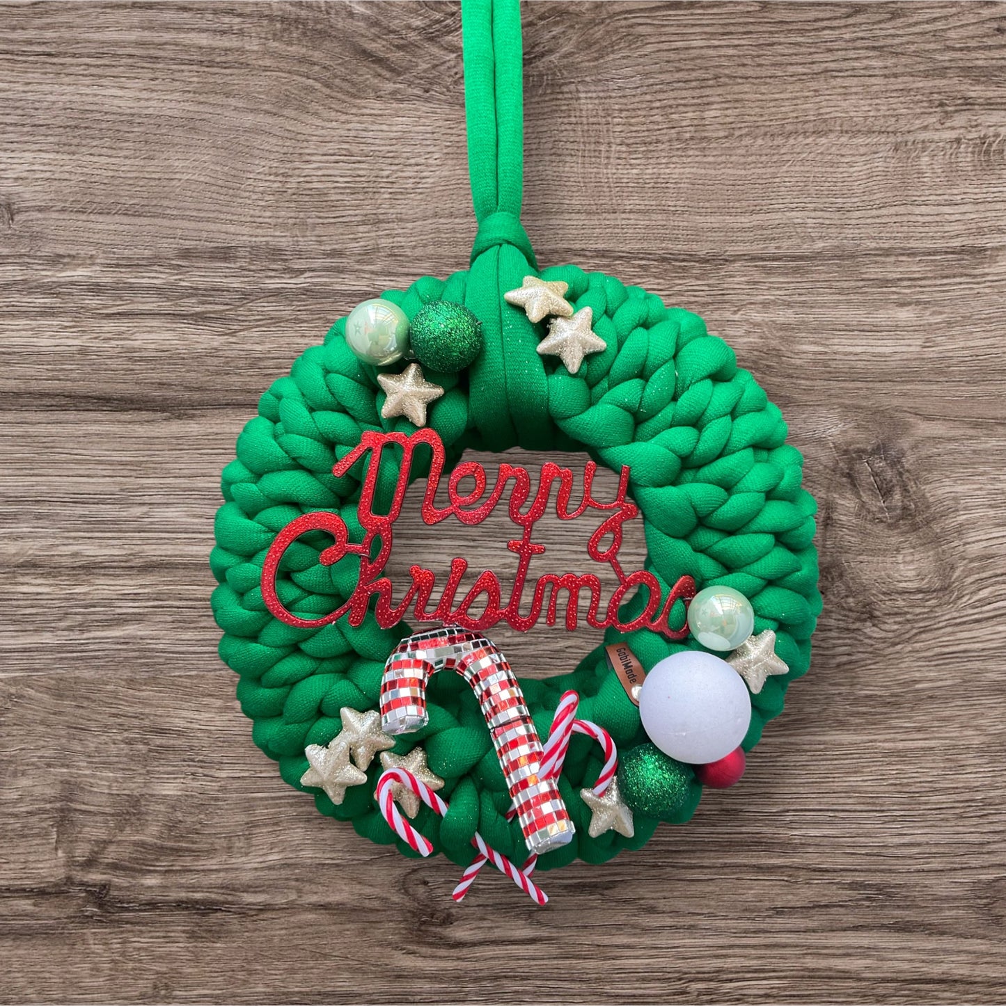 Ein gestrickter grüner Türkranz mit Dekoration 