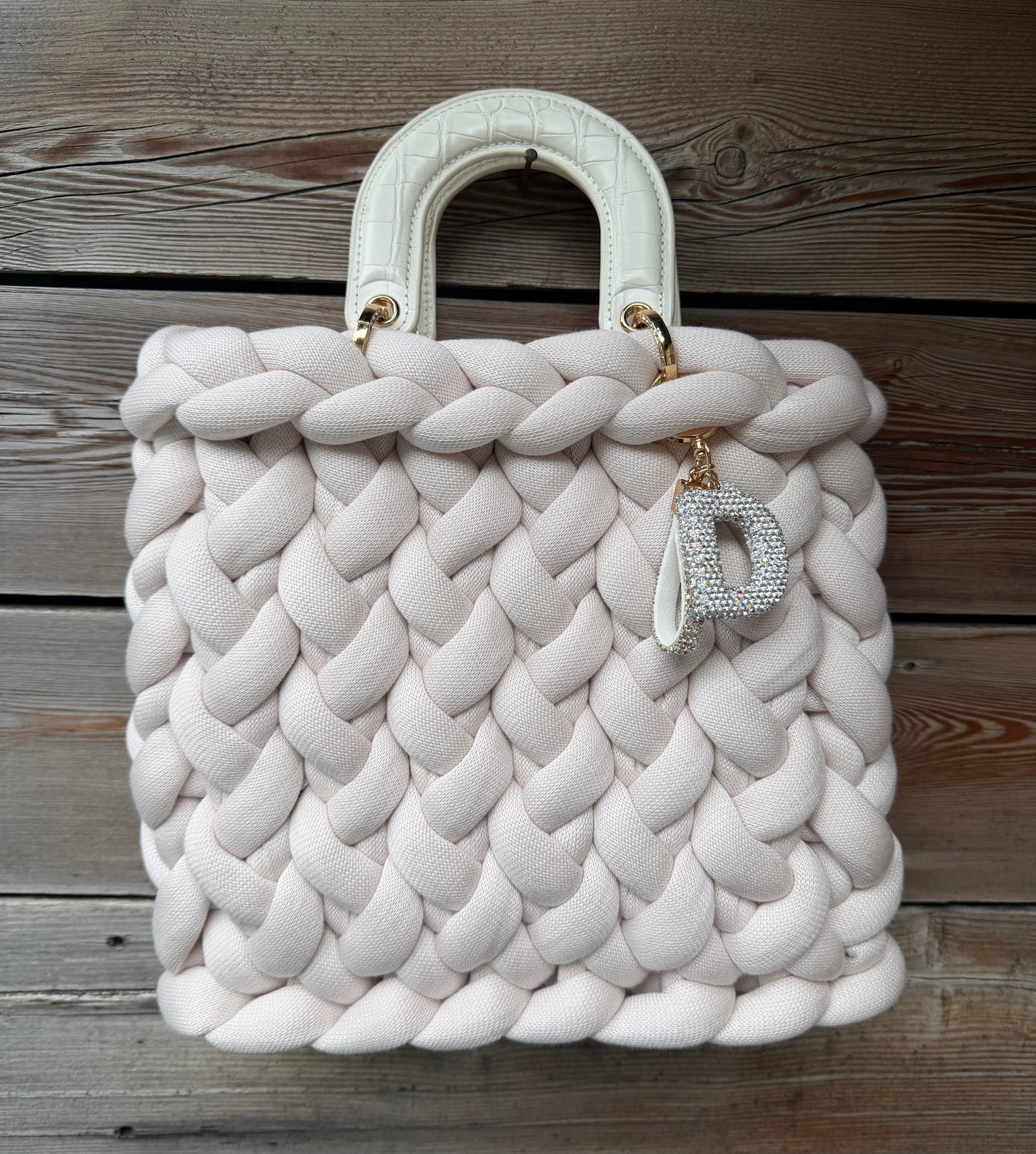 Eine Beige gestrickt Tasche mit Henkeln und Anhänger 