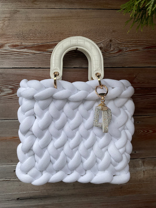 Eine gestrickte weiße Tasche mit Anhänger und henkel