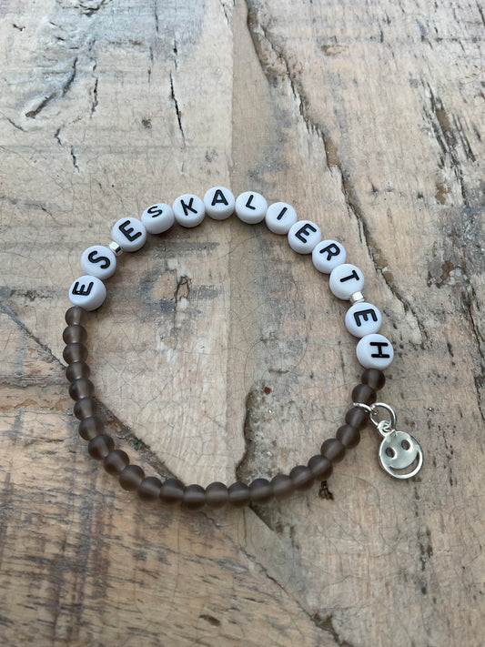 Ein Perlenarmband mit Schrift und Smileyanhänger 