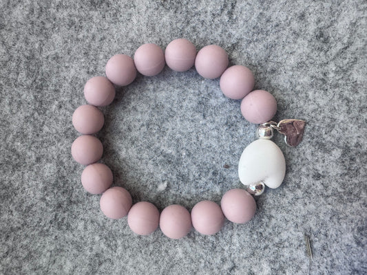 Ein Armband aus nudefarbene Silikonperlen . weißem Silikonherz und einem Herzanhänger.