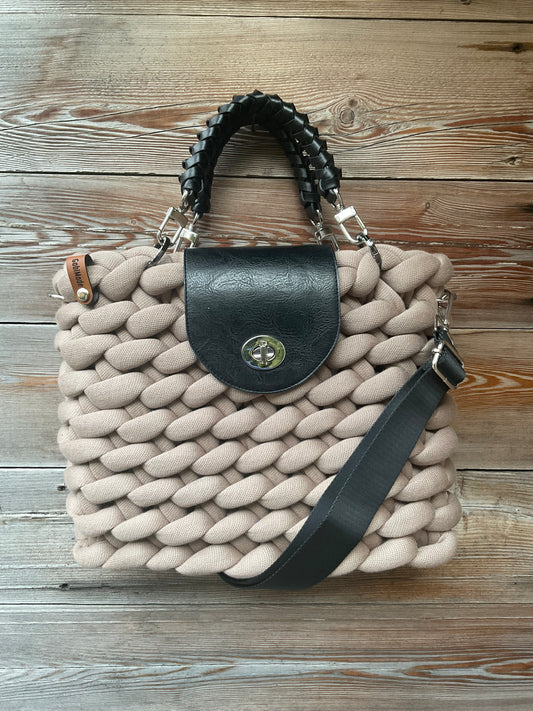 Eine gestrickte Tasche in geige mit Klappe und Griffen 