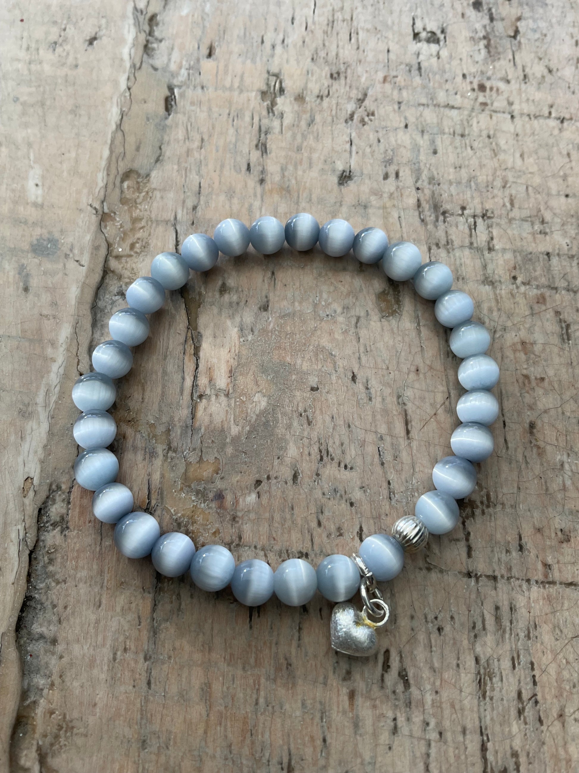 Ein graues perlenarmband mit Herzanhänger 