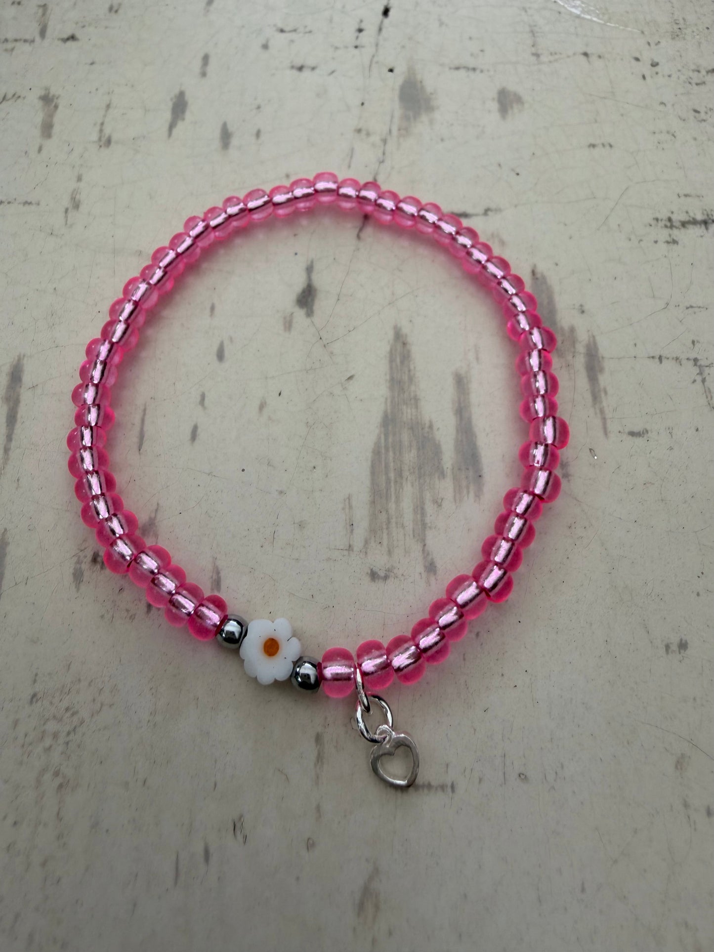 Ein pinkes Perlenarmband mit Blume und Herz