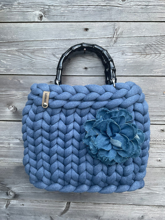 Eine gebrauchte blaue Tasche mit Blumenbrosche 